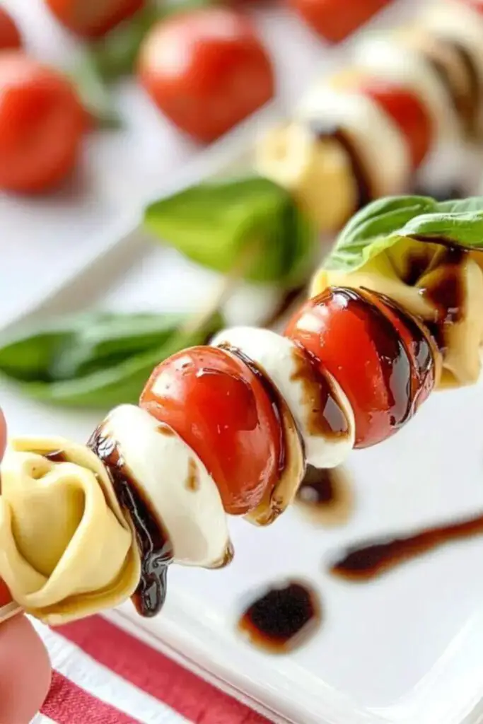 Tortellini Caprese skewers featuring Italian Christmas ingredients like fresh mozzarella balls, cherry tomatoes, basil leaves, and tortellini pasta, all drizzled with a balsamic glaze, perfect for a traditional Italian Christmas appetizer.