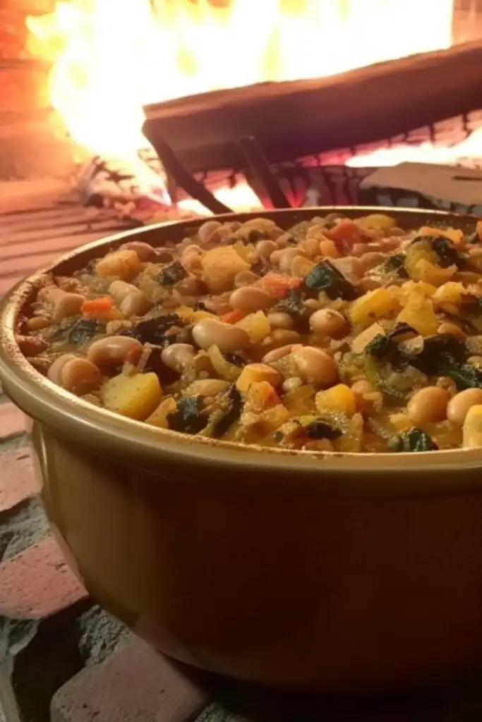 A hearty bowl of Tuscan bread and vegetable soup, filled with beans, kale, potatoes, and topped with rustic bread slices, perfect for a comforting meal.