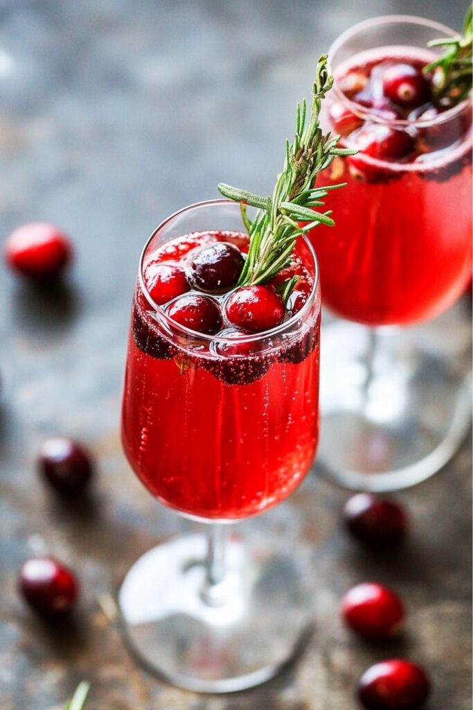 Festive Cranberry Bellini garnished with fresh rosemary and cranberries, served in a glass with a sparkling red hue, perfect for an Italian-inspired Christmas celebration.