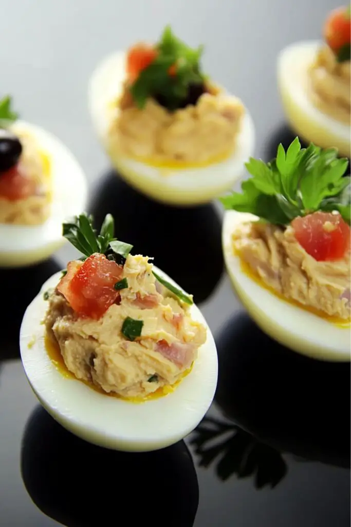 Deviled eggs topped with confit tuna, olives, and diced tomatoes, served as a flavorful Italian Christmas Eve appetizer, perfect for adding a touch of tradition to your holiday table.