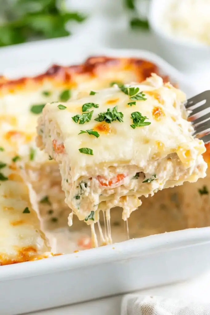 Close-up of a creamy seafood lasagna slice topped with melted cheese and garnished with fresh herbs, perfect for a traditional Italian Christmas Eve dinner. This dish features layers of pasta, seafood, and a rich sauce, ideal for Italian Christmas Eve dinner menu ideas.