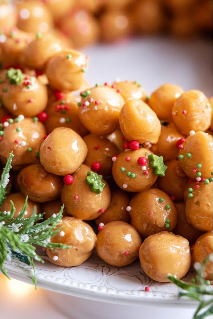 A close-up of Struffoli, traditional Italian Christmas sweets made of fried dough balls coated in honey and decorated with festive sprinkles.