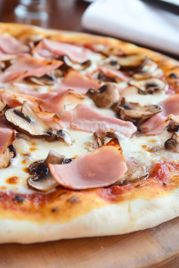 A classic pizza with ham and mushrooms, featuring a golden crust topped with savory ham, sliced mushrooms, and melted cheese, exemplifying the deliciousness of Italian pizza recipes.