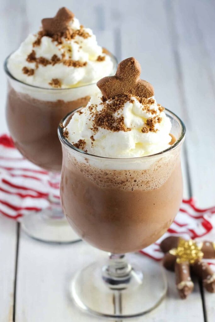 A frosty glass of frozen gingerbread hot chocolate topped with whipped cream and sprinkles, ideal for a holiday snack for kids.