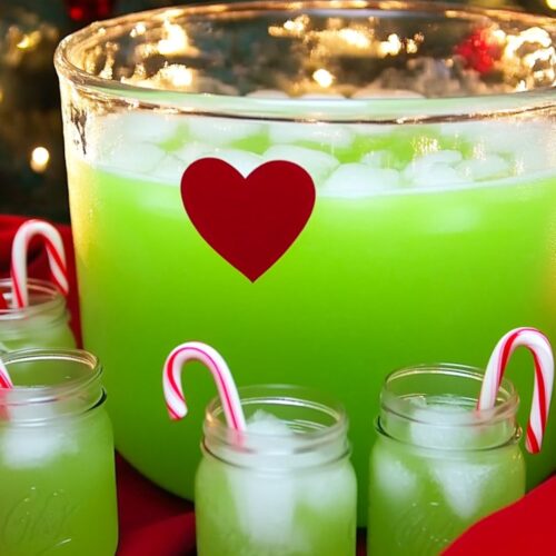 A bright green Grinch-themed punch in a clear glass with a red rim, perfect for a kids' Christmas party drink.