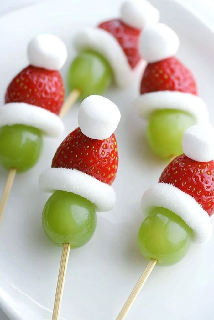 Fruit kabobs made with grapes, bananas, and strawberries to resemble the Grinch, perfect for Christmas snacks for kids' school party.