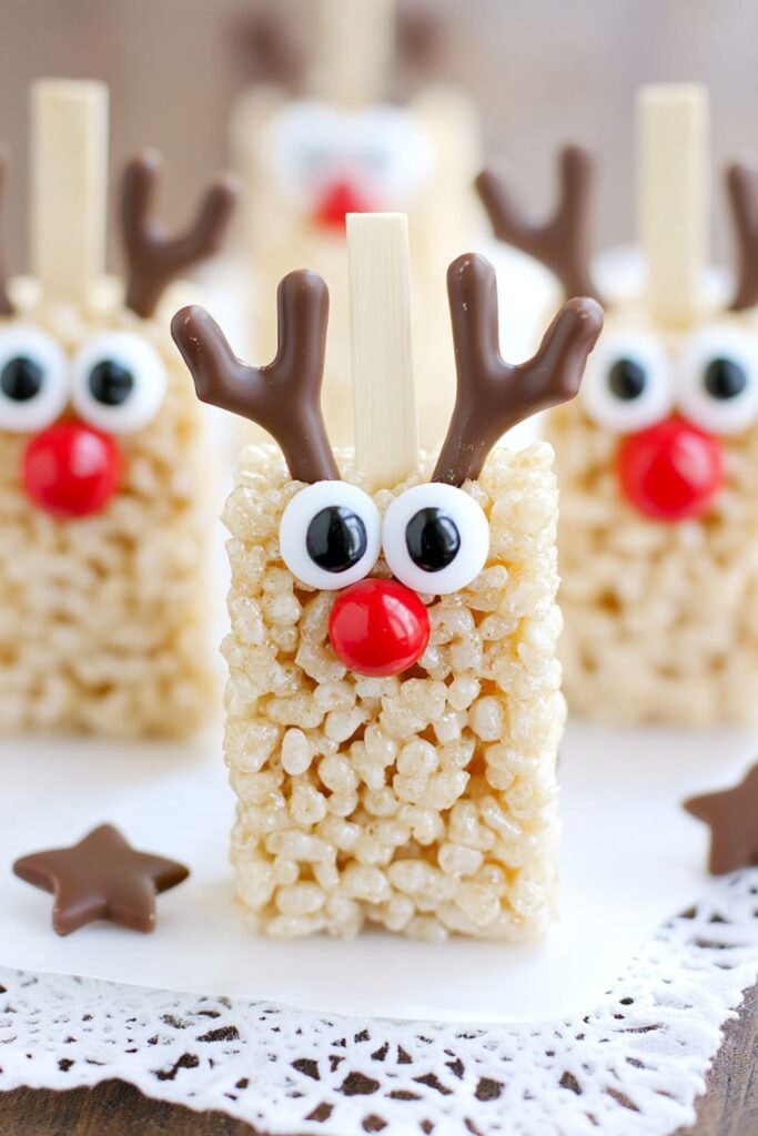 Rice Krispie treats decorated to look like reindeer faces with candy eyes, red noses, and pretzel antlers, ideal for kids’ Christmas snacks.