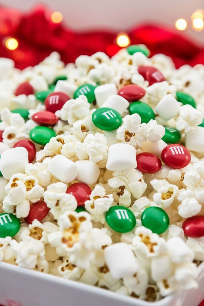 Bowl of Santa Crunch Popcorn with marshmallows, red and green candies, perfect for holiday movie nights.