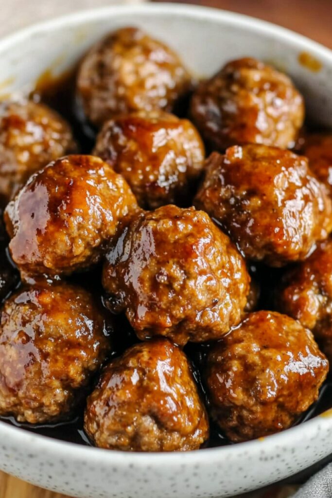 Sweet and tangy make-ahead meatballs arranged on a platter with toothpicks for Super Bowl Sunday.