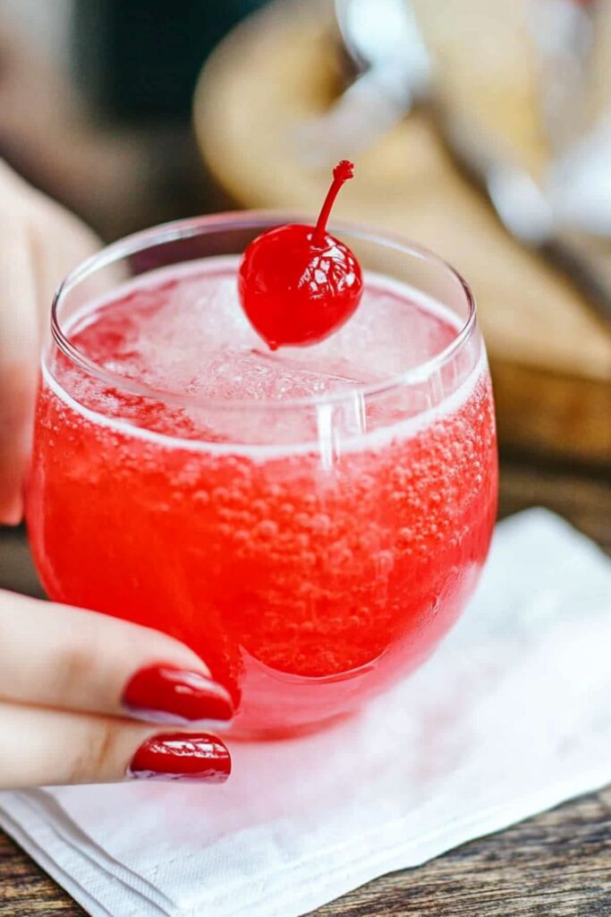 A fizzy cherry bomb mocktail served in a glass with a cherry garnish, perfect for Valentine’s Day cocktails without alcohol.