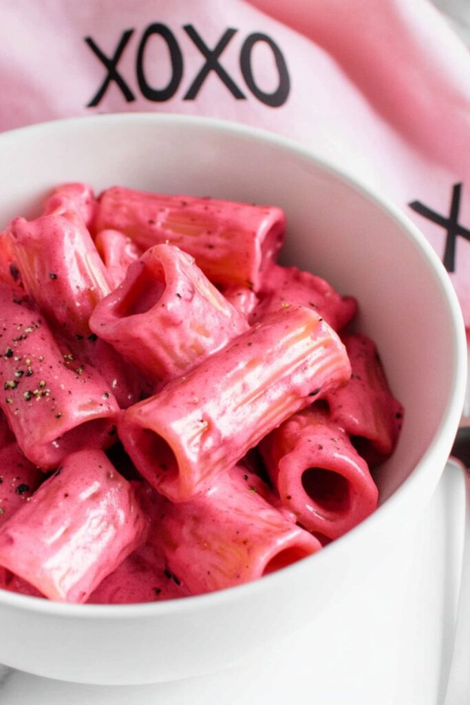 A bowl of creamy roasted garlic and beet pasta, perfect for a romantic classic Valentines day dinner or intimate gathering.