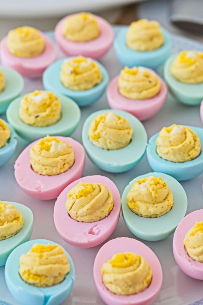 Colorful pastel-dyed deviled eggs on a platter, a creative example of Italian Easter Food.