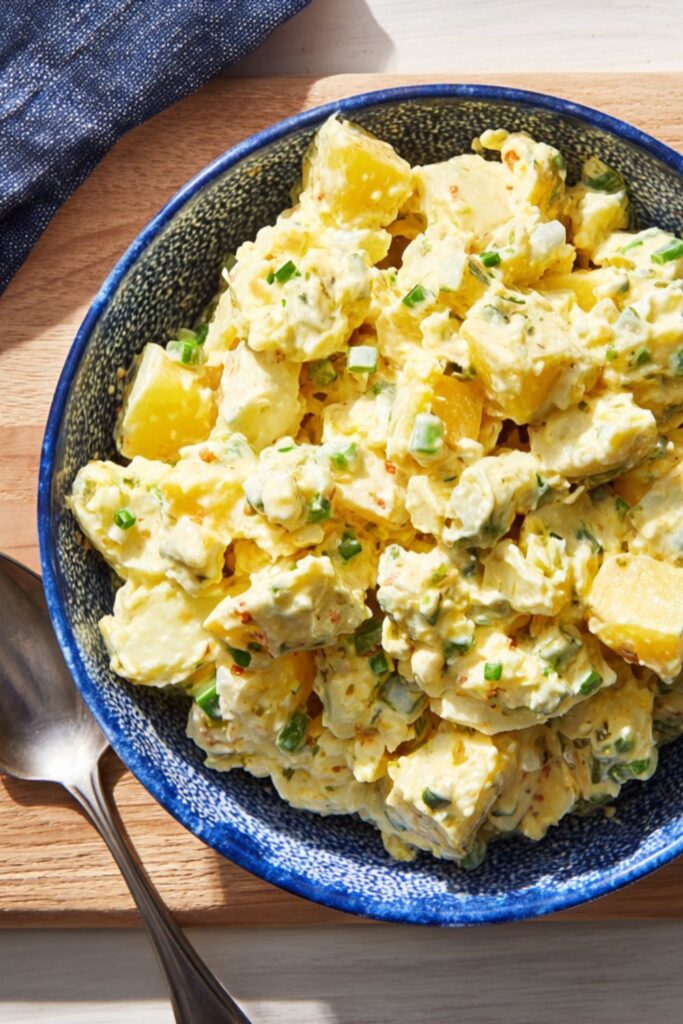 A bowl of creamy potato salad with green onions, serving as a classic picnic food.