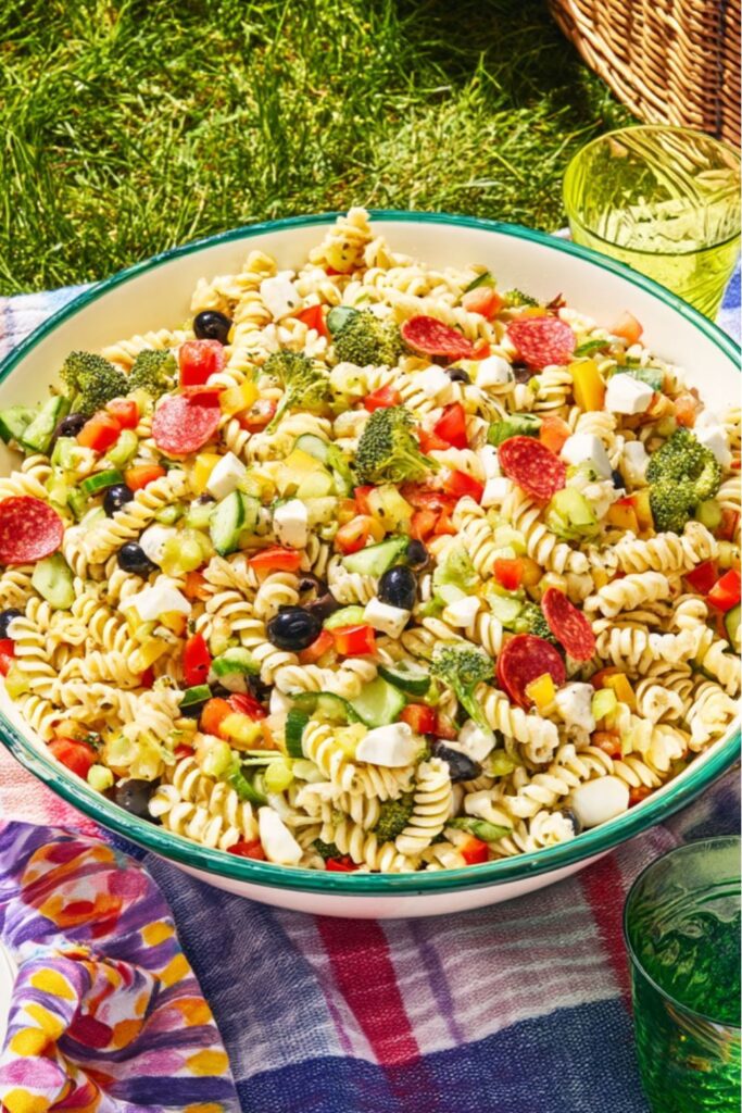 A large bowl of rotini pasta salad with pepperoni and broccoli, perfect for picnic side dishes.