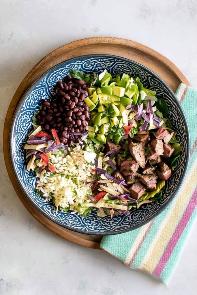A vibrant steak taco salad with black beans and avocado, a highlight among bbq salads.
