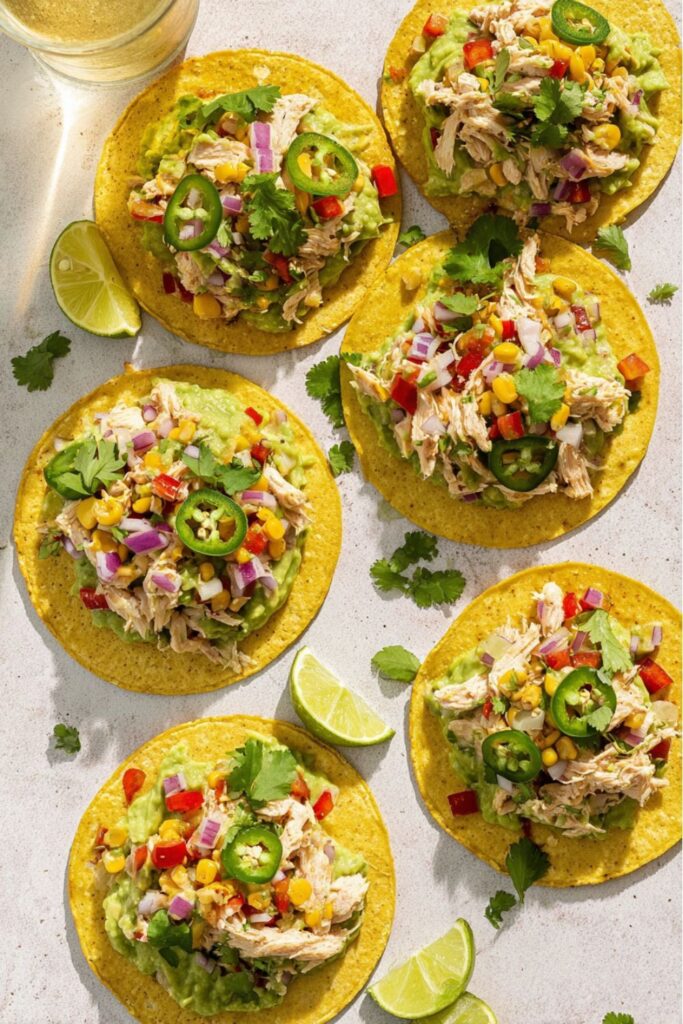 Crispy corn tortilla chicken tostadas topped with fresh avocado, corn, and jalapeño slices.