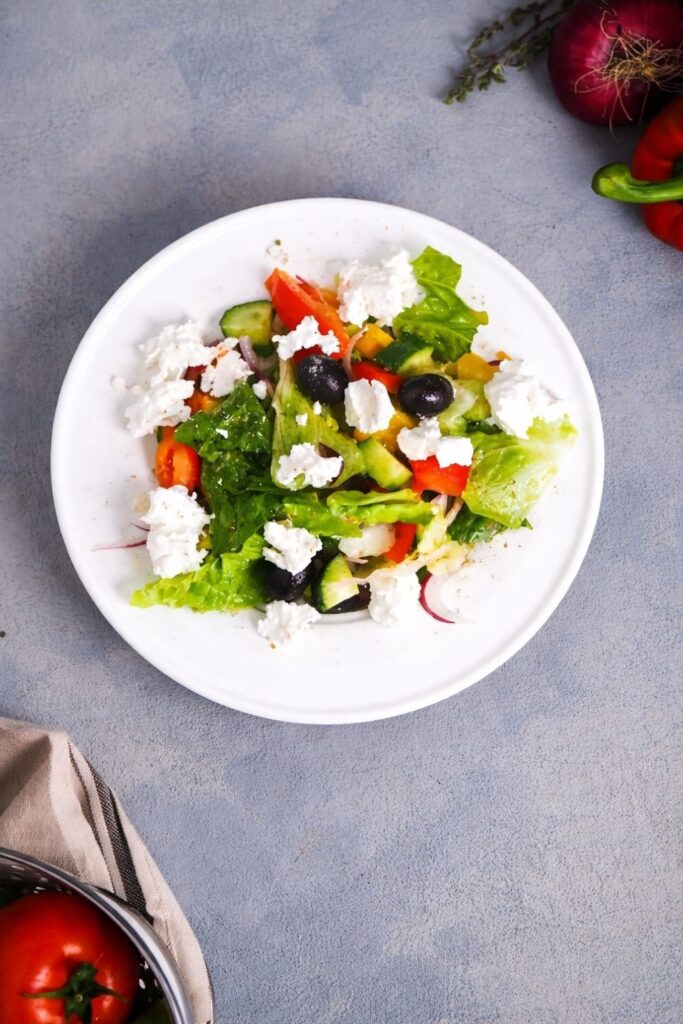 A crisp Greek salad with feta cheese, olives, and vegetables on a plate.