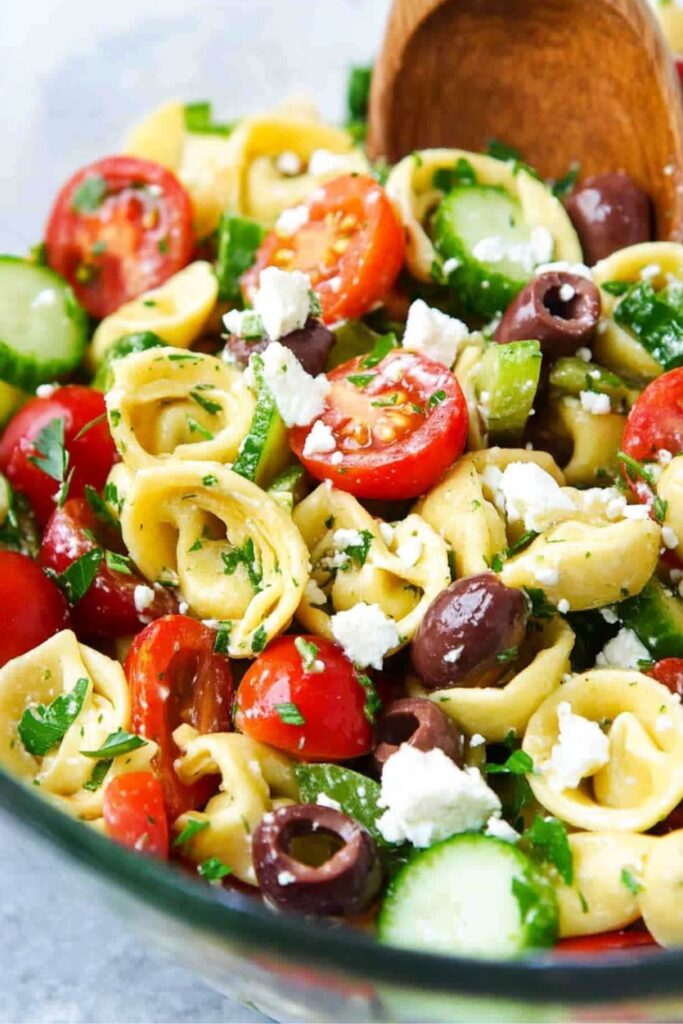 Colorful cheese tortellini salad with fresh vegetables, Kalamata olives, and feta cheese.