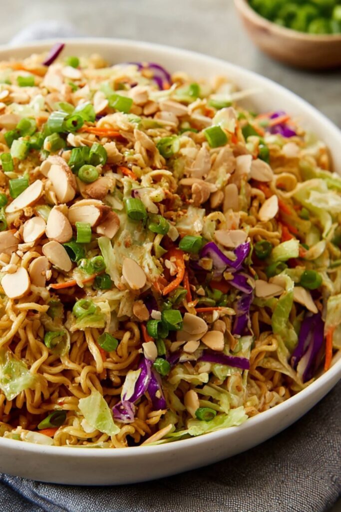 Bowl of crunchy ramen salad with shredded cabbage, carrots, green onions, and toasted almonds.