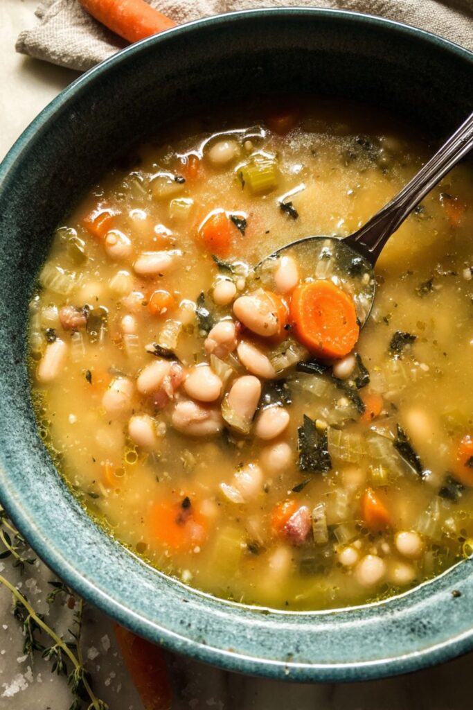 A rustic bowl of cannellini bean soup with pancetta, leeks, carrots, celery, and Parmesan, inspired by Ina Garten soup recipes from the best Ina Garten recipes collection.