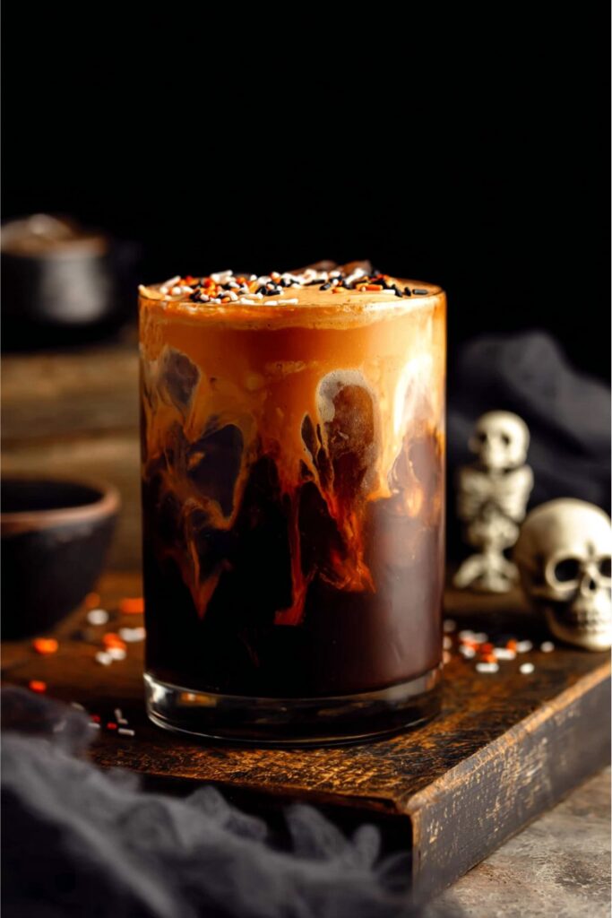 A glass of cold brew coffee topped with bright orange pumpkin spice cold foam and festive Halloween sprinkles, perfect for Halloween coffee drinks and fall coffee ideas.