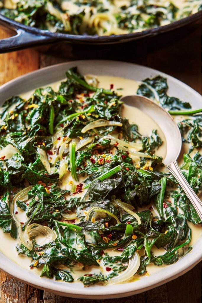 Creamy sautéed greens with onions and garlic in a skillet, made with coconut milk and miso paste, a flavorful vegan Thanksgiving vegetable side dish.