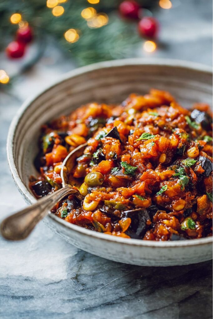 A vibrant bowl of Sicilian-style eggplant caponata filled with golden eggplant cubes, olives, capers, raisins, and herbs—an inviting choice for Italian Christmas dinner ideas.