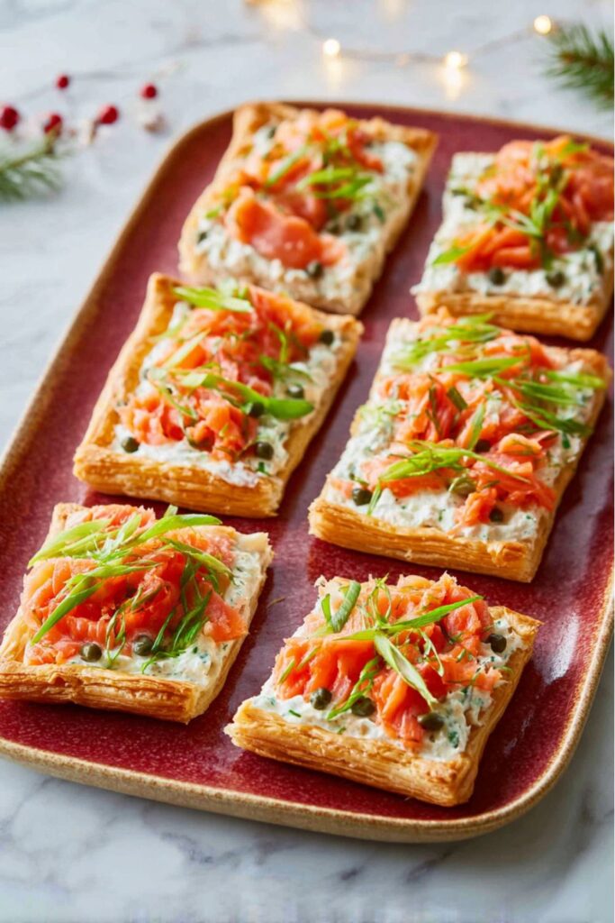 A golden puff pastry tart topped with creamy cheese spread, smoked salmon, scallions, and capers, sliced into festive wedges—an elegant dish perfect for Italian Christmas dinner ideas.