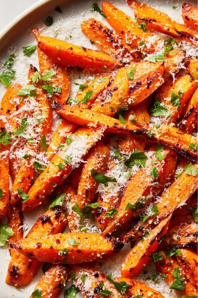 Roasted carrots coated with Parmesan and garlic, garnished with parsley and lemon juice, served on a platter as a flavorful Thanksgiving vegetable side dish.