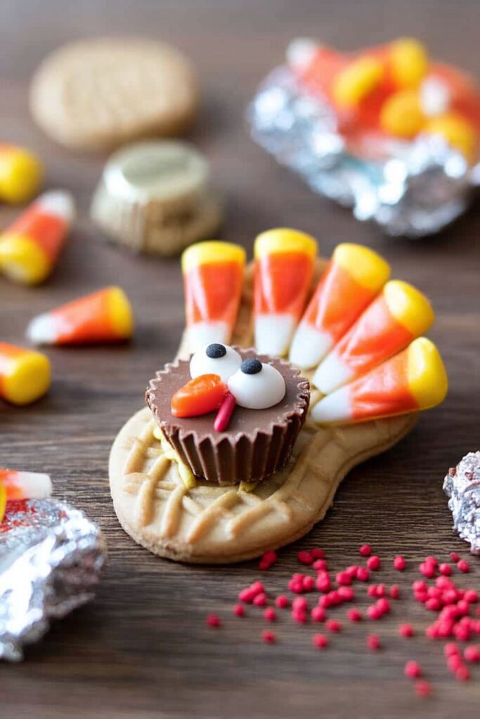 Nutter Butter turkey cookies decorated with candy corn feathers, peanut butter cups, candy eyes, and red sprinkles as fun Thanksgiving school treats for kids.