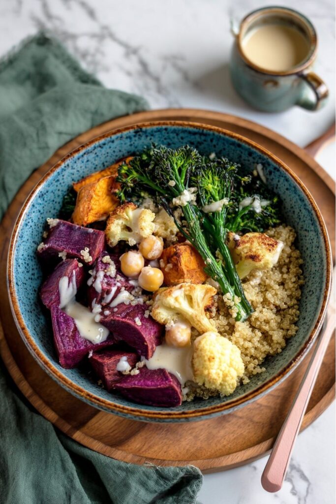 Vegan Quinoa Bowl Recipes: A visually striking quinoa bowl with roasted purple sweet potatoes, cauliflower, broccolini, chickpeas, and a generous drizzle of creamy tahini sauce.
