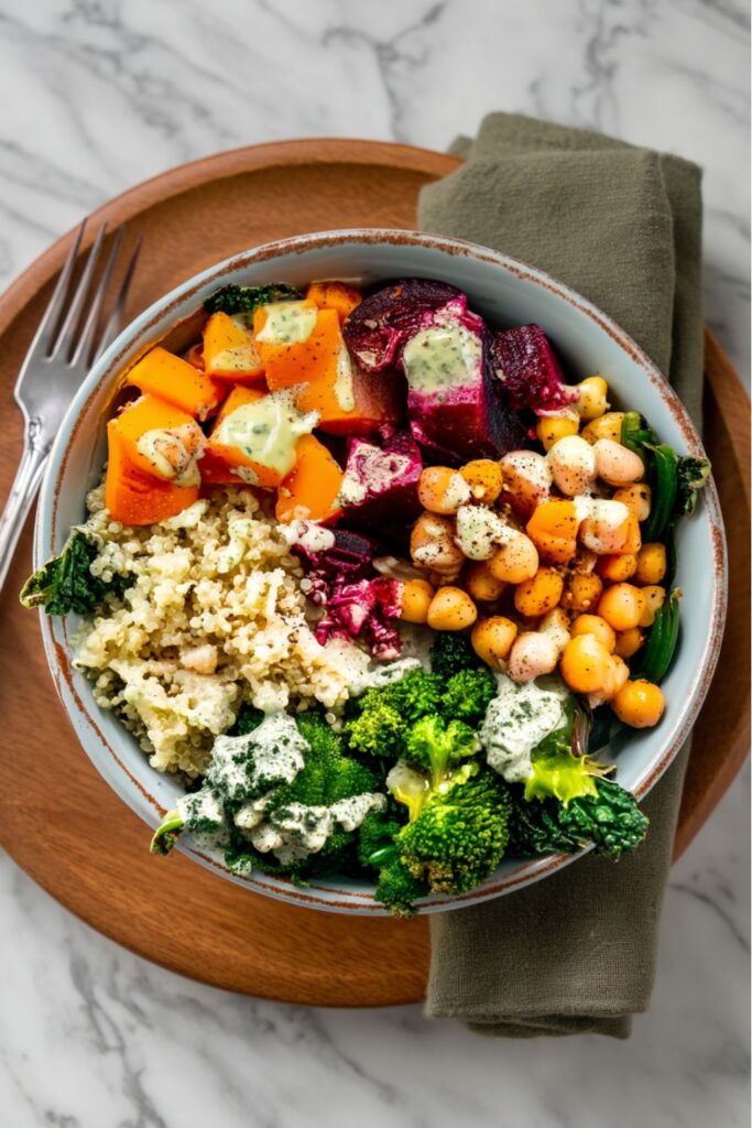 High Protein Veganuary Recipes: A hearty quinoa bowl featuring roasted butternut squash, beets, steamed broccoli and greens, and a mix of white beans and chickpeas, topped with a creamy dressing.