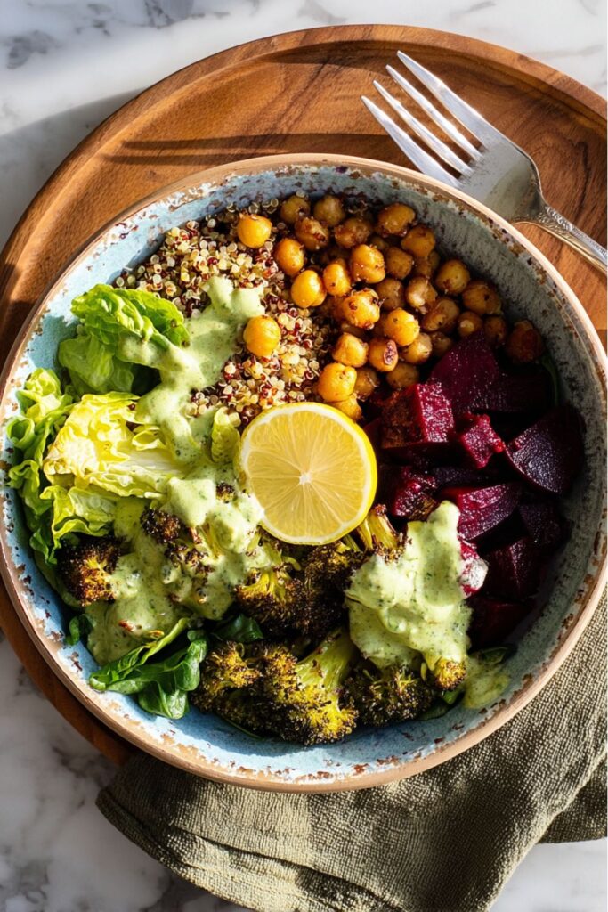 Healthy Veganuary Meals: A vibrant vegan quinoa bowl with roasted chickpeas, diced beets, roasted broccoli, crisp lettuce, and a slice of lemon, drizzled with a creamy green dressing.