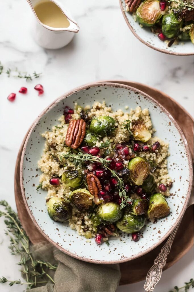 Veganuary Quinoa Recipes: A bowl of warm quinoa topped with roasted Brussels sprouts, pecans, fresh thyme, and pomegranate seeds, drizzled with a light dressing.