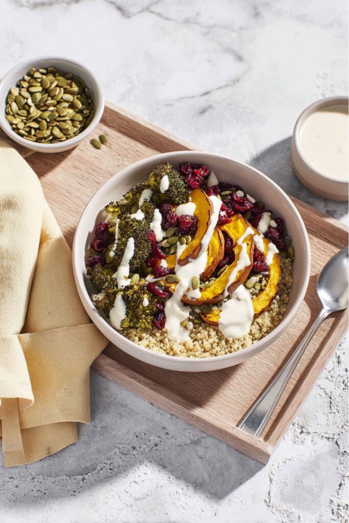 A vibrant quinoa bowl topped with roasted delicata squash, charred broccoli, and a creamy cashew dressing, perfect for Winter Meal Ideas Vegetarian.