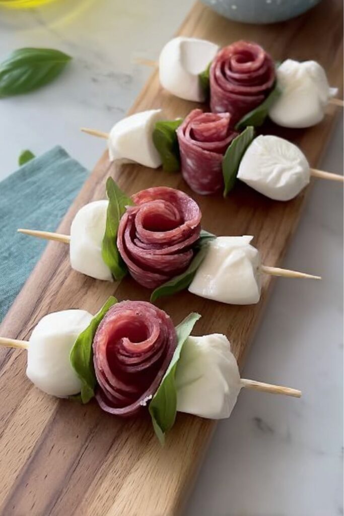 Salami rose and mozzarella skewers, a creative example of Italian antipasto ideas on wood.