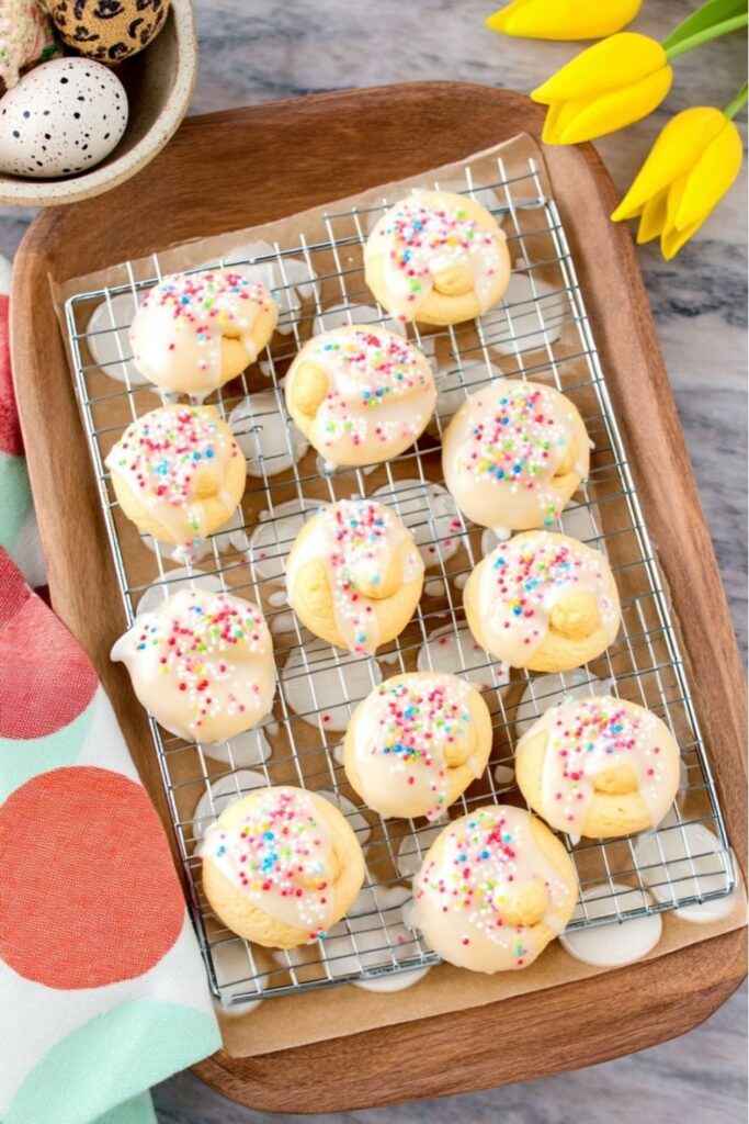 A tray of knotted cookies from various Italian Easter Recipes topped with glaze and sprinkles.