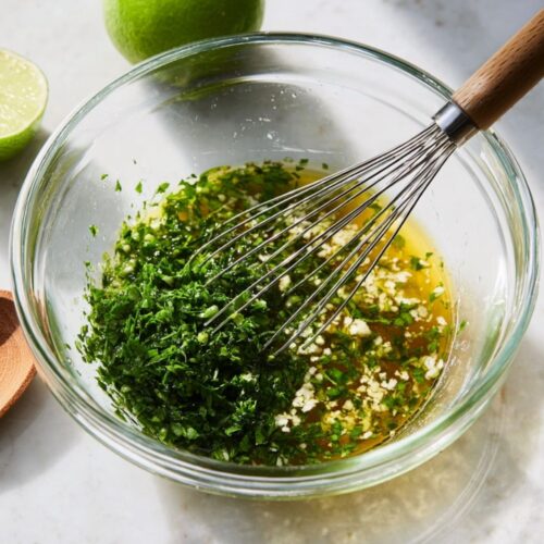 Whisking a cilantro and lime juice dressing in a glass bowl for Fiesta Rice Salad.