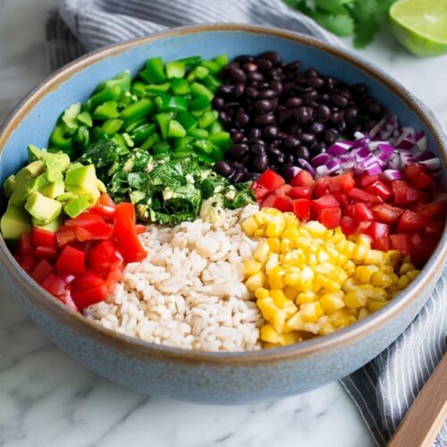 A blue bowl filled with colorful arranged ingredients for a Fiesta Rice Salad.