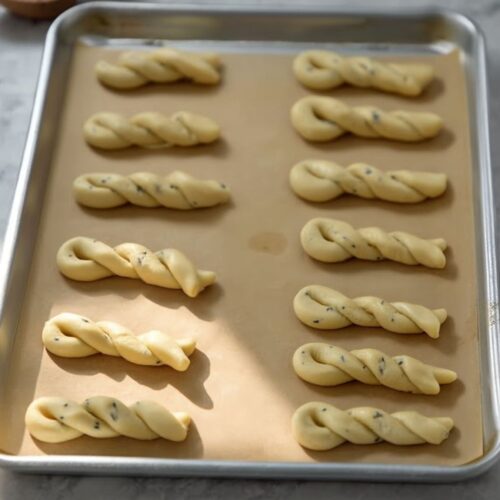 A white lace stand holds colorful, textured bunny cookies beside bowls of pastel candy eggs.