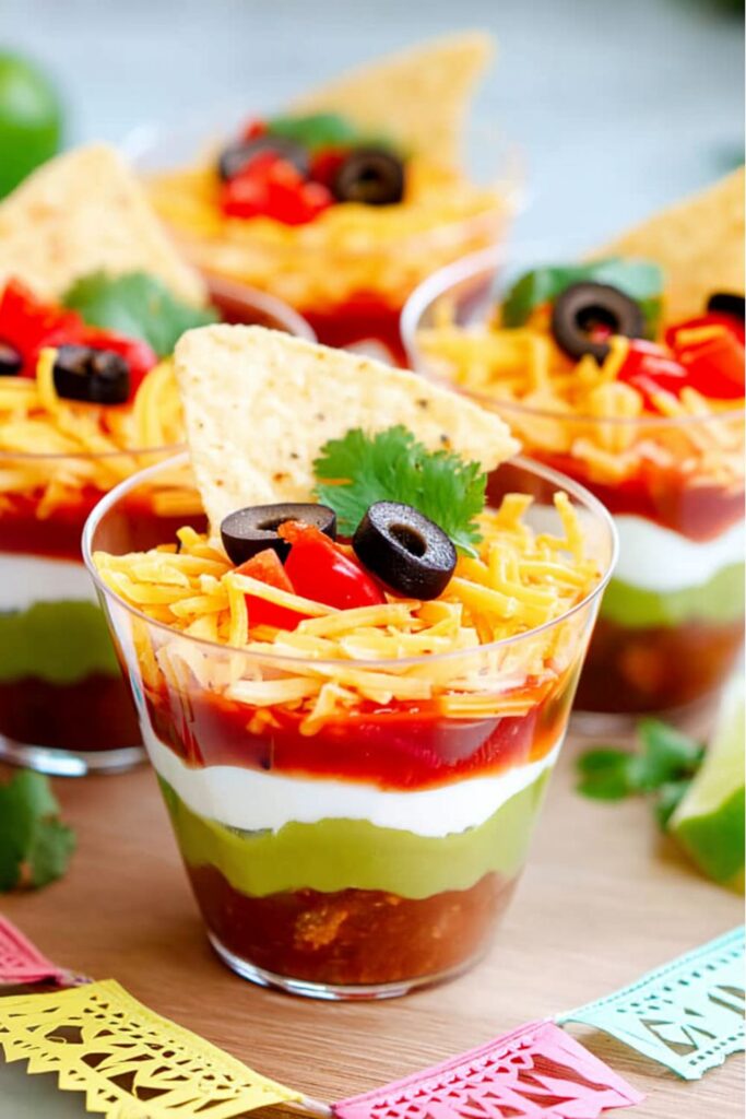 Layered taco dip cups with chips, fun Kid-Friendly Buffet Ideas for kids.