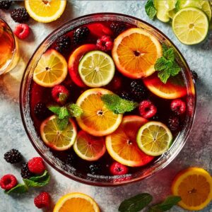 Mother’s Day punch with citrus slices, berries, and mint in a glass bowl.