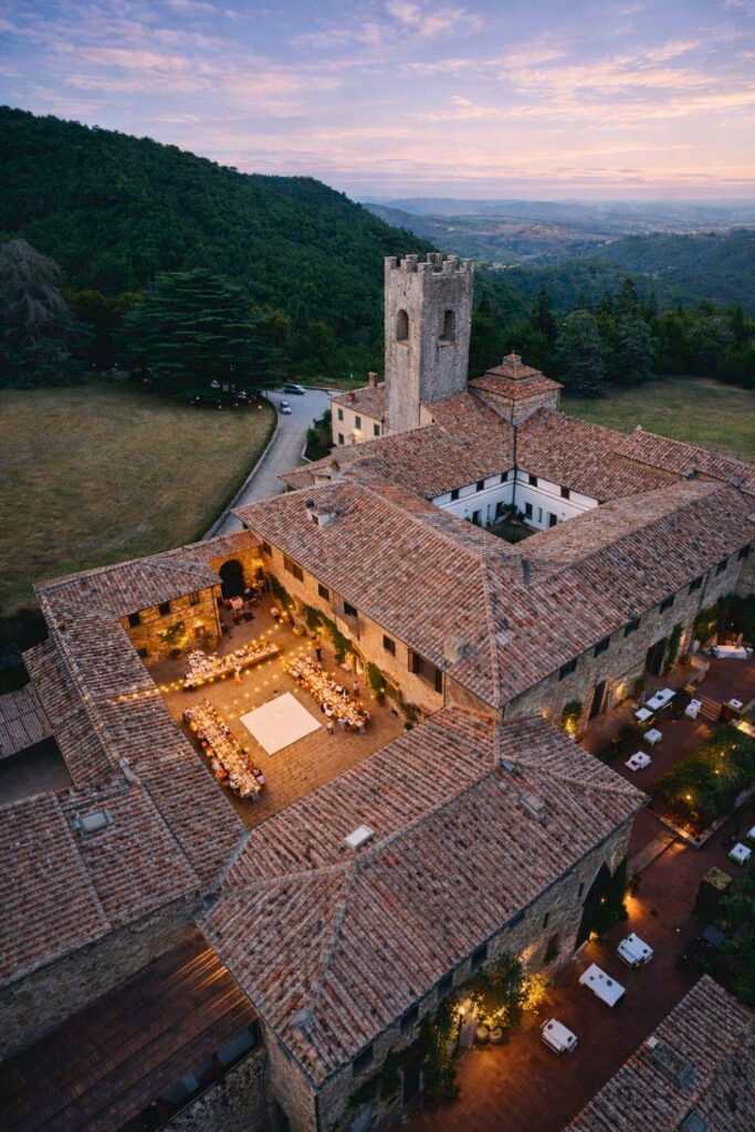 Aerial view of Vineyard Hotels in Tuscany at Badia a Coltibuono wine resort, with abbey roofs and lit courtyard