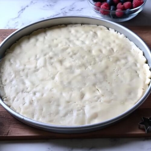 Sugar cookie dough slices pressed into a pizza pan to form an American Flag Fruit Pizza crust.