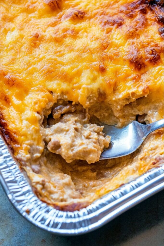Creamy baked refried bean dip with melted cheese on top for usa appetizers.