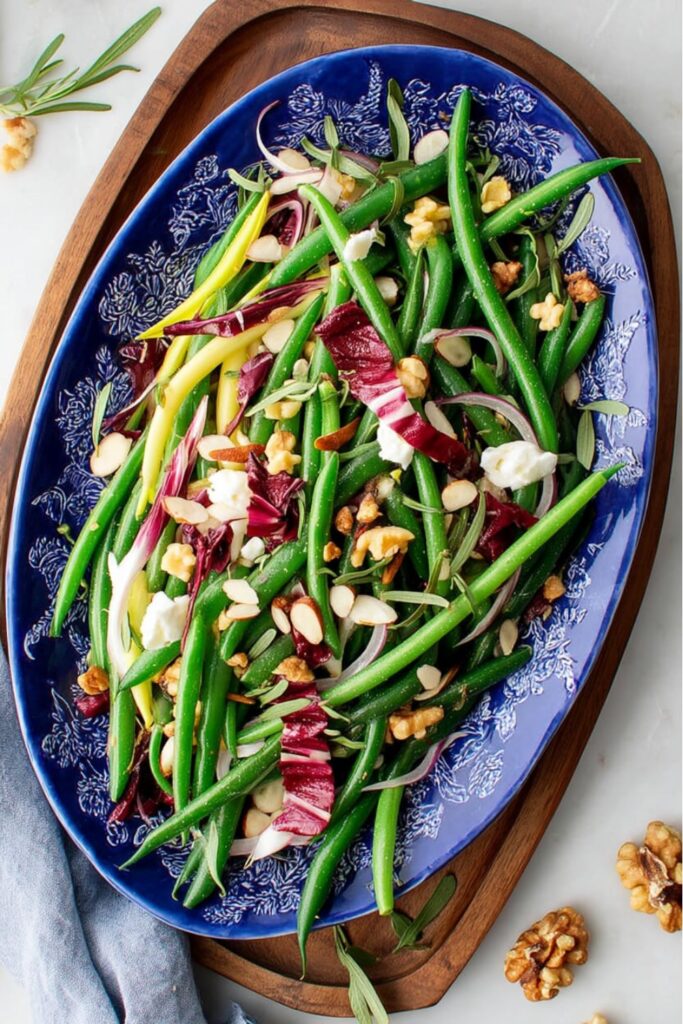 A blue platter with green bean salad and goat cheese, perfect picnic side dishes.
