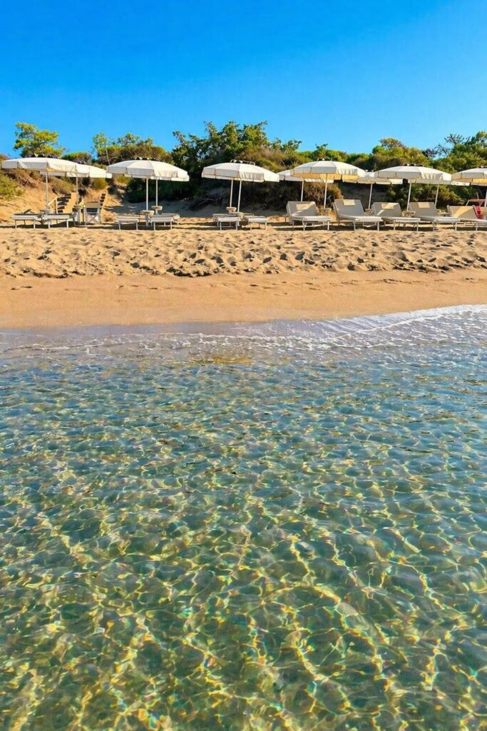 Riva del Sole Resort & Spa shore with clear water and white umbrellas, a classic Beach Hotels in Tuscany view