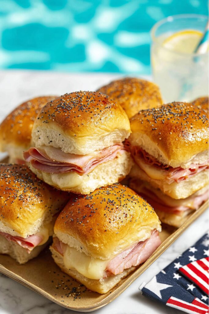 Ham and Swiss sliders with poppy seeds on a tray, an ideal Fourth Of July Toddler Snacks.