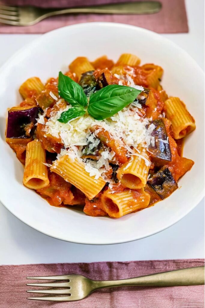 Rigatoni pasta coated in rich tomato marinara sauce topped with roasted eggplant and fresh basil.