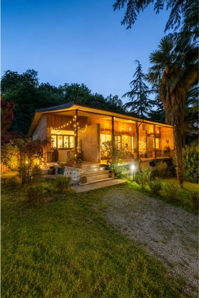 Tuscany Airbnb cottage glowing at twilight for Where to stay in Tuscany with garden trees